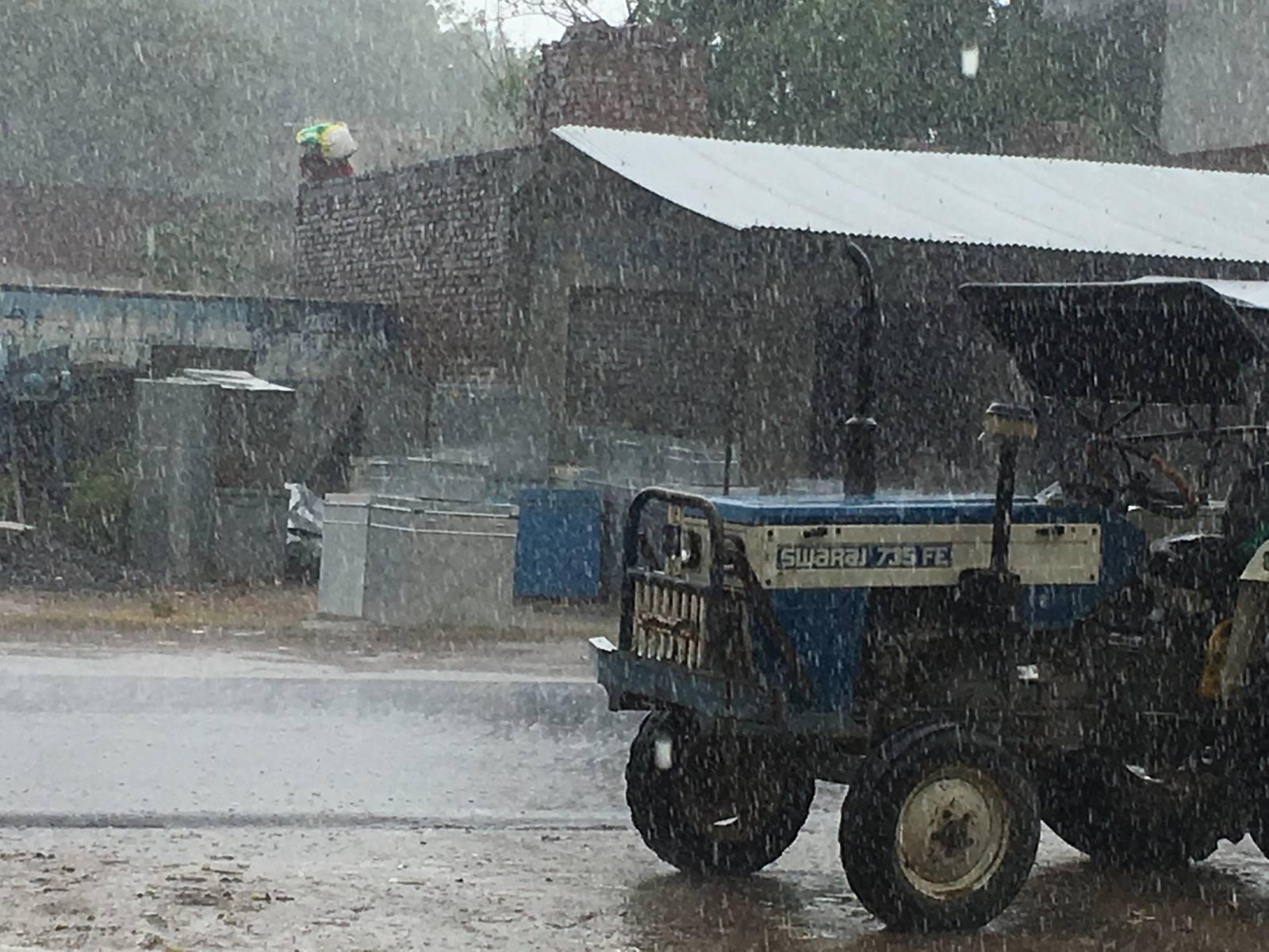 A tractor standing in heavy monsoon rain in rural India
